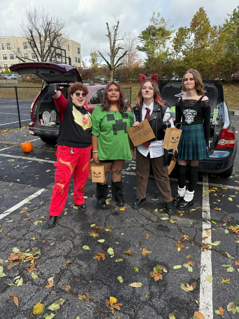 group of four people dressed up for halloween stand in front of vehicle trucks during Truck or Treat